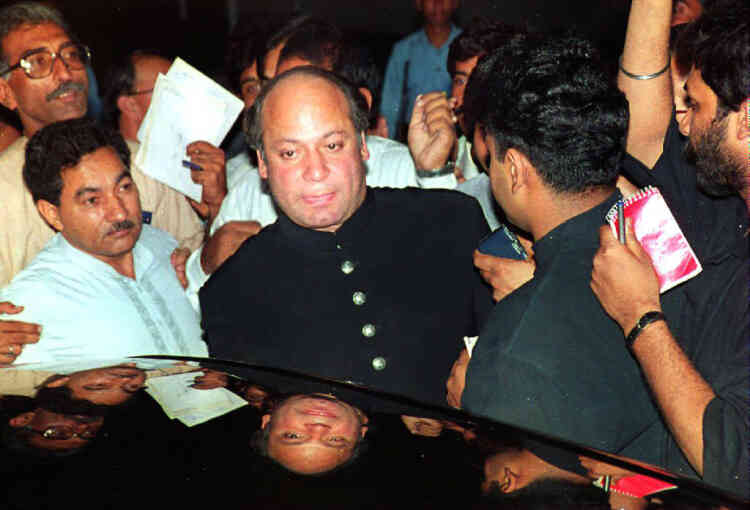 Former Pakistani Prime Minister Nawaz Sharif (C) tries to avoid journalists outside the presidency 19 July 1993 in Islamabad, Pakistan after he witnessed the oath taking ceremony of interim premier Moeen Qureshi. Sharif stepped down as prime minister a short time before his political rival President Ishaq Khan announced his resignation.