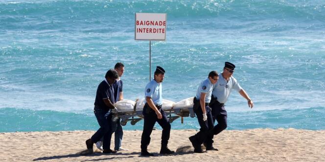 Des gendarmes transportent le corps du surfeur français tué par une attaque de requin mercredi 8 mai sur la plage de Saint-Gilles à l'île de La Réunion.