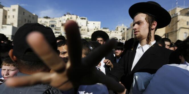Un policier retient des juifs ultra-orthodoxes venus protester contre les prières de femmes devant le mur des lamentations, à Jérusalem le 10 mai. 