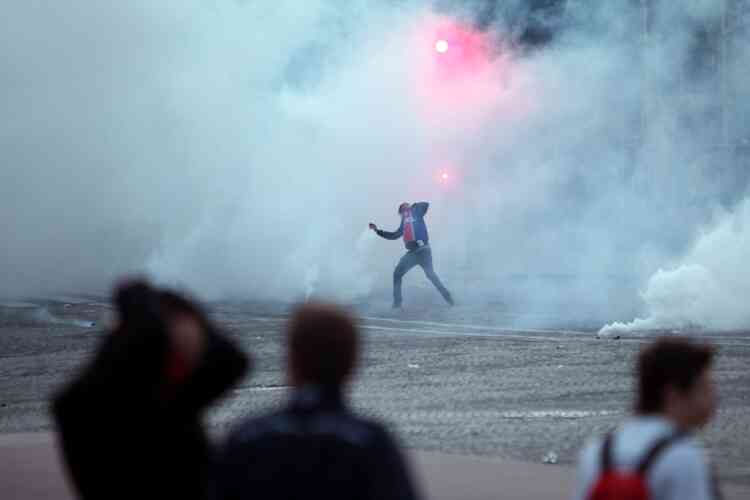 A Paris Saint Germain supporter throws a gas canister back to riot police officers during clashes after the celebration of PSG's French League title, in Paris, Monday, May 13, 2013. Paris Saint-Germain clinched its first French league title since 1994 by defeating Lyon 1-0 on Sunday. PSG has now an unassailable seven-point lead at the top of the standings. With just two rounds left, second-place Marseille can no longer catch its fierce rival. (AP Photo/Thibault Camus)