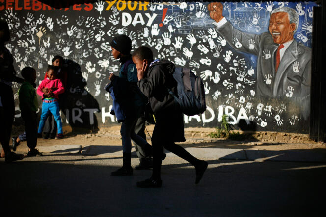 Des écoliers sud-africains passent devant une fresque murale représentant Nelson Mandela dans le township d'Alexandra, à Johannesburg, jeudi 13 juin