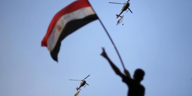 Des hélicoptères de l'armée égyptienne déploient le drapeau national sous les applaudissements de la foule réunie place Tahrir, le 1er juillet au Caire.