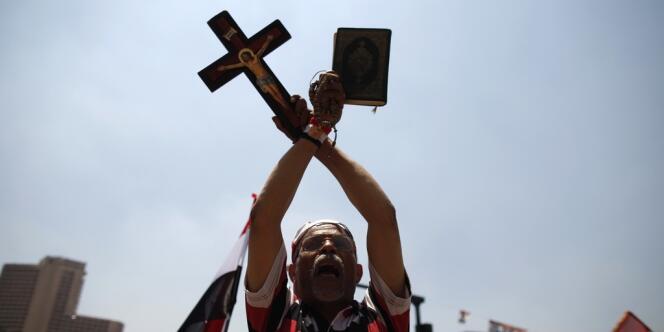 Un opposant à Morsi brandit une copie du Coran et une croix chrétienne durant un rassemblement place Tahrir, vendredi 5 juillet.
