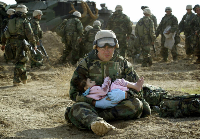 Le 29 mars 2003, un marine tient une petite fille irakienne dans ses bras après que son unité a tiré sur un véhicule de civils, tuant la famille de l’enfant. Ce véhicule était poursuivi par des tireurs irakiens, ce qui le forçait à se diriger vers la base américaine.