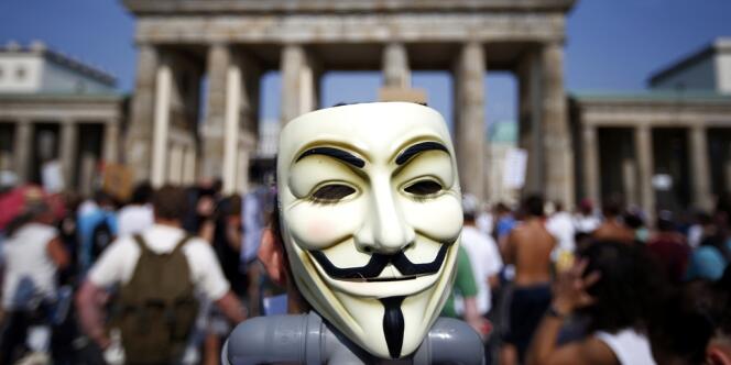 Un masque de Guy Fawkes brandi devant la porte de Brandebourg à Berlin le 27 juillet 2013, en protestation contre le programme de surveillance Prism. 