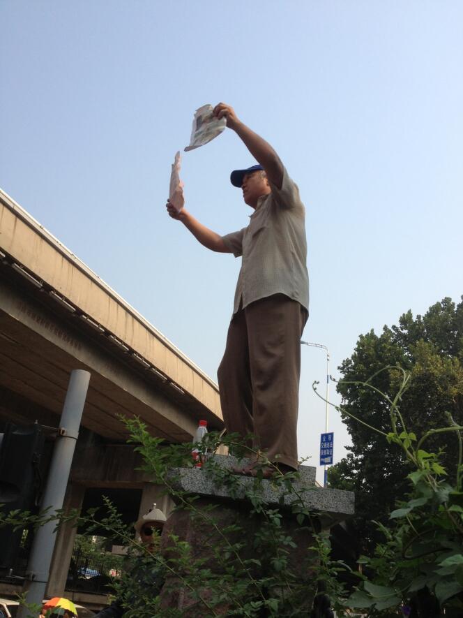 Un manifestant agitant une pétition aux abords du tribunal de Jinan, jeudi 22 août.