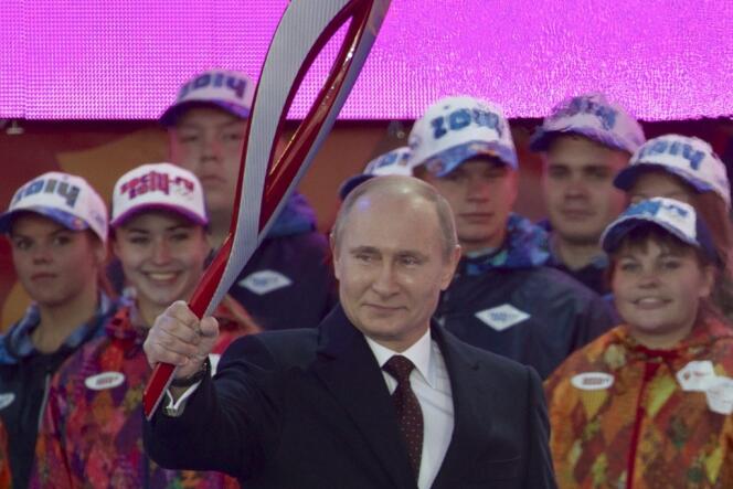 Le président Vladimir Poutine brandit la flamme olympique, dimanche 6 octobre, sur la place Rouge, à Moscou.