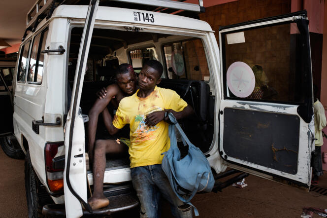 Un homme aide son compagnon à sortir d'un véhicule de Médecins Sans frontières à l'hôpital communautaire de Bangui.