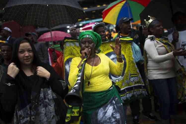 A woman plays a vuvuzela while others sing and dance at a mass memorial for late former South African President Nelson Mandela at the First National Bank Stadium in Johannesburg December 10, 2013. World leaders, from U.S. President Barack Obama to Cuba's Raul Castro, will pay homage to Mandela at the memorial that will recall his gift for bringing enemies together across political and racial divides.REUTERS/Ronen Zvulun (SOUTH AFRICA - Tags: POLITICS OBITUARY)
