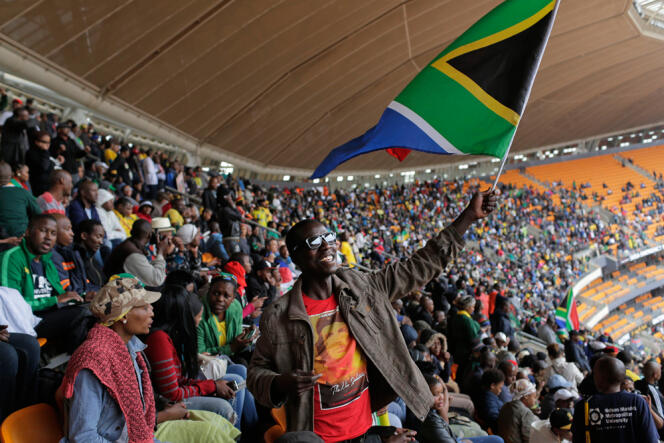 Un homme brandissant un drapeau sud-africain dans le stade de Soweto pour l'hommage à Mandela.