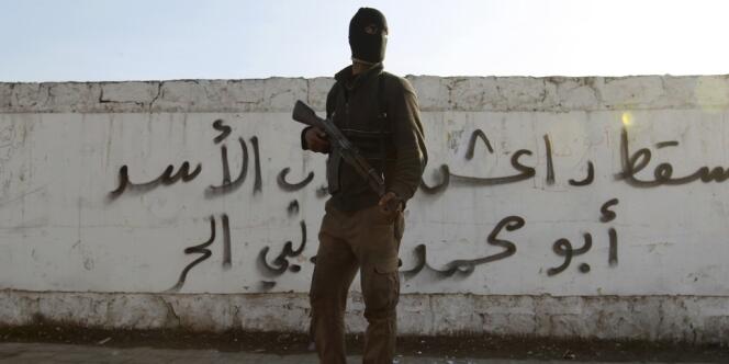 Un combattant de l'Armée syrienne libre pose devant un graffiti « A bas Da'ech » (« l'Etat islamique en Irak et au Levant », djihadiste), le 7 janvier à Alep.
