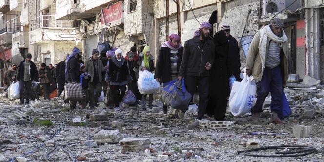 Des civils marchent vers le point de ralliement pour l'évacuation de la ville de Homs, le 7 février.
