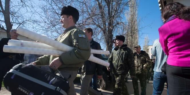 Des militaires ukrainiens quittent la base de Novofedorivka, en Crimée, prise par les forces armées et des civils prorusses, le 22 mars.