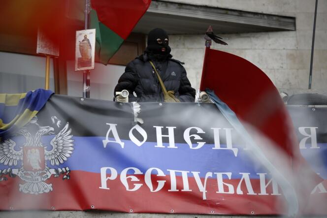 A Donetsk, dans l'est de l'Ukraine, un séparatiste au balcon de l'administration régionale occupée, au dessus d'un drapeau proclamant 