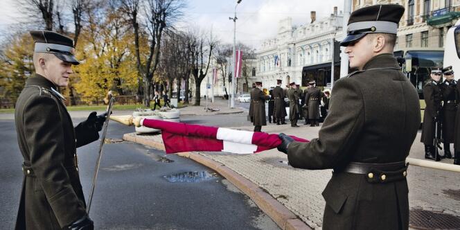 Deux soldats lettons roulent le drapeau national après une cérémonie, devant le monument  de la Liberté, à Riga. Ce pays balte de plus de  2 millions d'habitants compte 283 000 citoyens de seconde zone aux droits limités, car russophones. On les apelle parfois les 