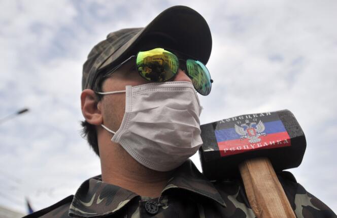Un prorusse portant une masse arborant un drapeau de la « République de Donetsk ».