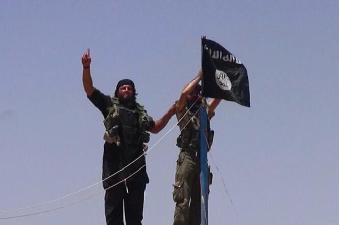 Des combattants de l'Etat islamique en Irak et au Levant (EIIL) hissent leur drapeau à un poste frontière entre l'Irak et la Syrie, le 11 juin.