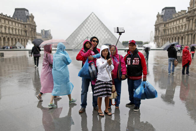 Des touristes font un selfie près de la pyramide du Louvre, à Paris, le 9 juillet. 