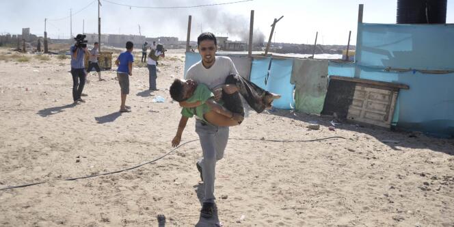 Un Palestinien transporte le corps d'un enfant tué par un bombardement israélien, le 16 juillet.