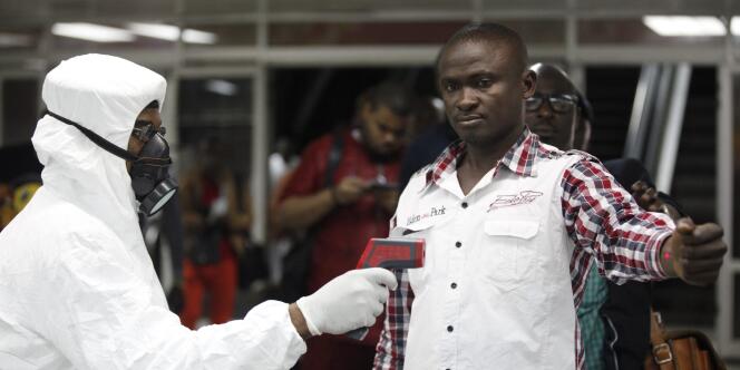 Un homme prend la température d'un voyageur à l'aéroport de Lagos, au Nigeria, le 6 août.