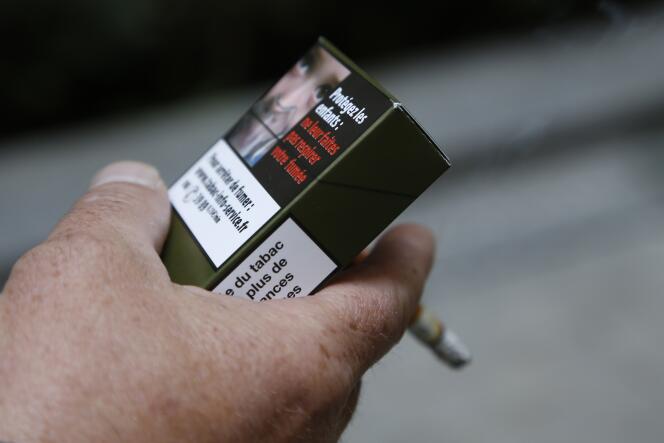 Un homme tenant un exemplaire de paquet de cigarettes neutre, proposé par l'association Alliance contre le tabac, en septembre 2014 à Paris.