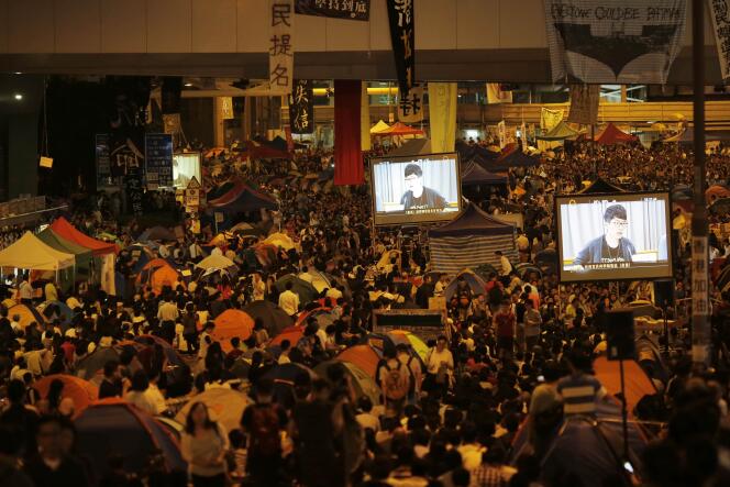 Des manifestants regardent dans la rue une retransmission des discussions entre gouvernement et étudiants à Hongkong mardi 21 octobre.