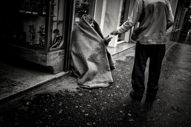 « Vous voulez que les pauvres soient des citoyens responsables ? Alors, permettez-leur d’être acteurs de leur avenir ! » (Photo: un passant donne une pièce de monnaie à un SDF qui se protège du froid avec une couverture, en décembre 2009 dans une rue du centre ville de Lyon).