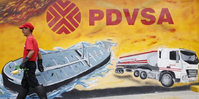 Un ouvrier passe devant une fresque murale ornée du logo de PDVSA, Petroleos de Venezuela, la compagnie pétrolière nationale, dans une station service de Caracas, le 29 août 2014.
