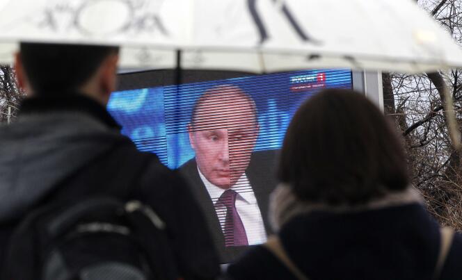 Des spectateurs regardent le discours de Vladimir Poutine sur un écran géant à Sébastopol.