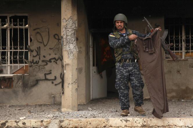 Un peshmerga brandi la tenue d'un combattant de l'Etat islamique tué pendant les combats au mont Sinjar, le 18 décembre.