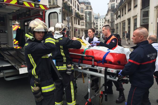 Des pompiers évacuent une victime devant le siège de Charlie Hebdo, à Paris.