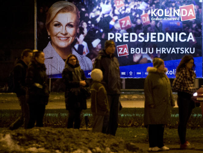 Des passants devant une affiche de Kolinda Grabar-Kitarovic, candidate conservatrice à l'élection présidentielle croate, le 9 janvier 2015, à Zagreb (Darko Bandic / AP).