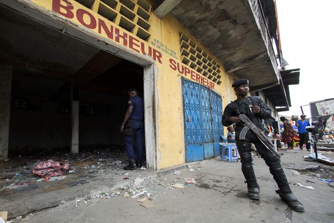 Un officier de police devant un magasin du centre de Kinshasa qui a été pillé durant les manifestations.