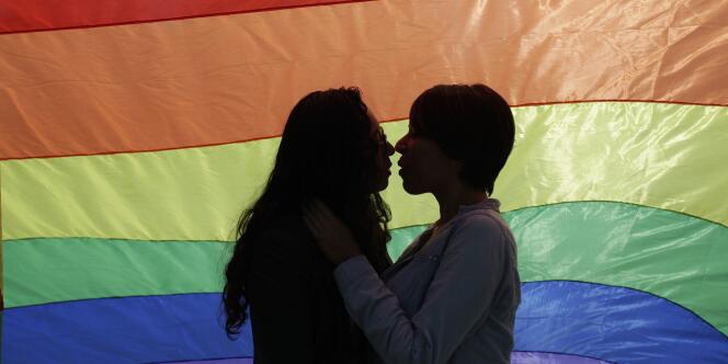 Un couple s’embrasse devant le rainbow flag, symbole de la communauté gay.