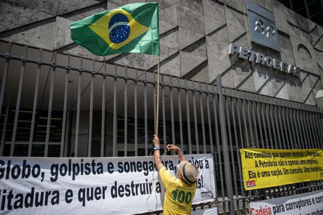 Un manifestant attache un drapeau brésilien au grillage entourant le siège de Petrobras, le 4 mars à Rio de Janeiro.