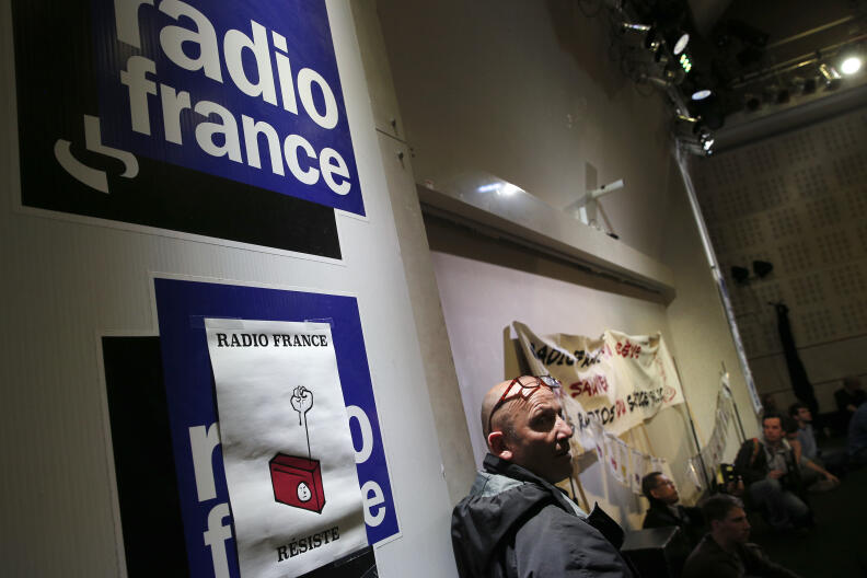 Employees of France's state radio corporation Radio France attend a strike meeting held at the company's headquarters in Paris, France, Friday, April 3, 2015. Journalists and media workers at Radio France have been on strike since Thursday, March 19 to oppose budget cuts and the potential cut of 300 jobs. The poster reads: "Radio France Resists". (AP Photo/Christophe Ena)