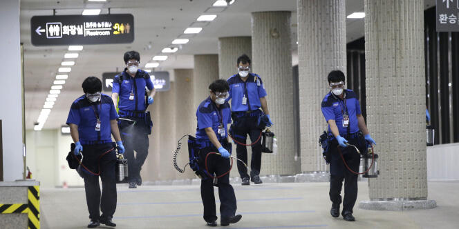 Des employés désinfectent le parking de l'aéroport international de Gimpo à Séoul, le 17 juin.