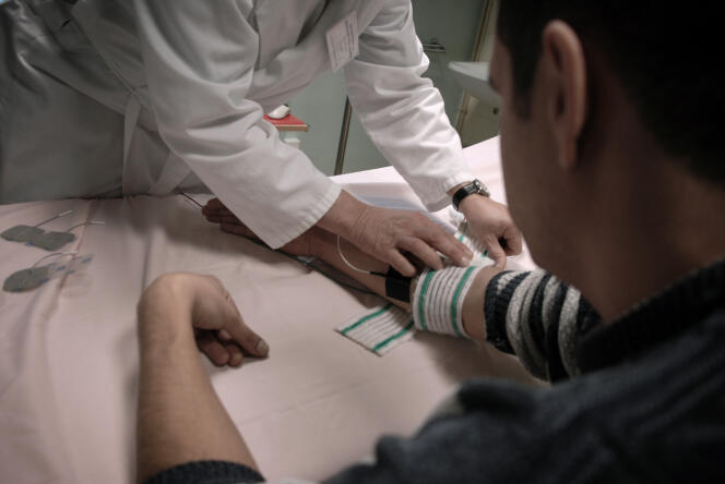 Un médecin psychiatre de l'hôpital Saint-Jean de Dieu à Lyon pose des électrodes sur le bras d'un patient.