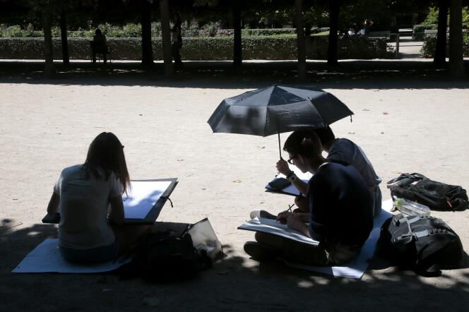 Des étudiants en art se protègent du soleil dans le jardin du Palais-Royal, à Paris, le 6 juillet 2015.