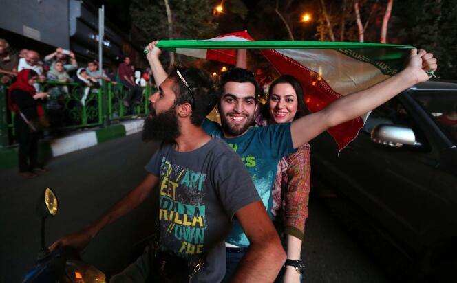 Des Iraniens agitent le drapeau lors des célébrations à Téhéran, le 14 juillet 2015.