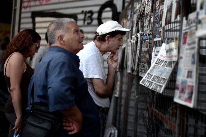 Des Grecs lisent les titres de la presse à Athènes, le 31 juillet.