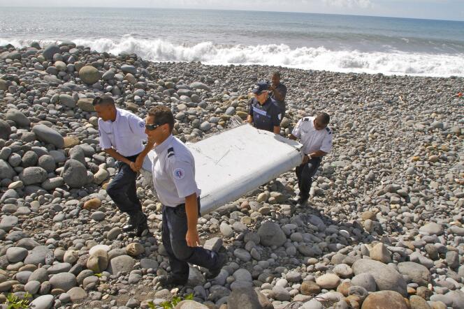 Des gendarmes transportent un fragment d’aile d’avion retrouvé sur une plage de La Réunion, mercredi 29 juillet.