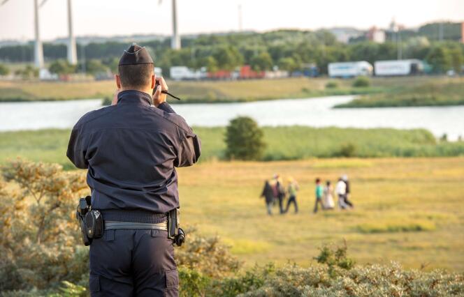 Un gendarme surveille un groupe de migrants tentant d'entrer sur le site d'Eurotunnel à Calais, vendredi 31 juillet.