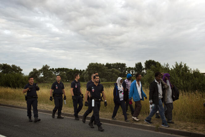 Des policiers français encadrant des migrants désireux de passer en Angleterre par le tunnel sous la Manche, en août 2015, près de Calais.