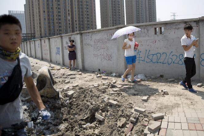 Des passants regardent des débris projetés dans les rues de Tianjin après les explosions sur le site portuaire, le 13 août 2015.