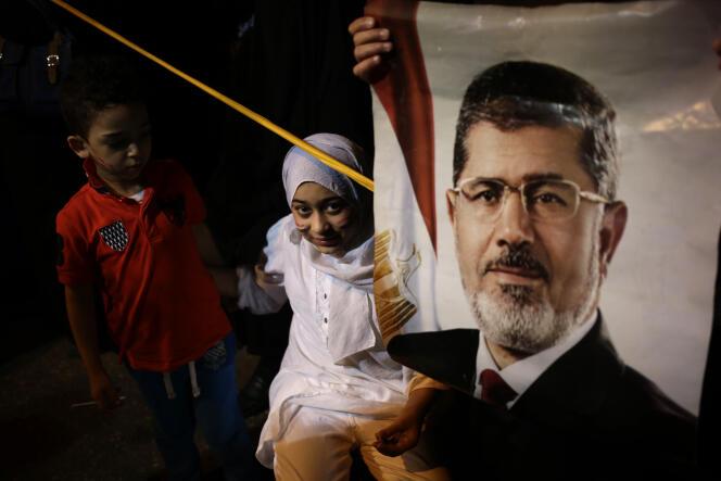 Des enfants de partisans des Frères musulmans campent près d'un poster à l’effigie de le Mohammed Morsi, en juillet 2013.
