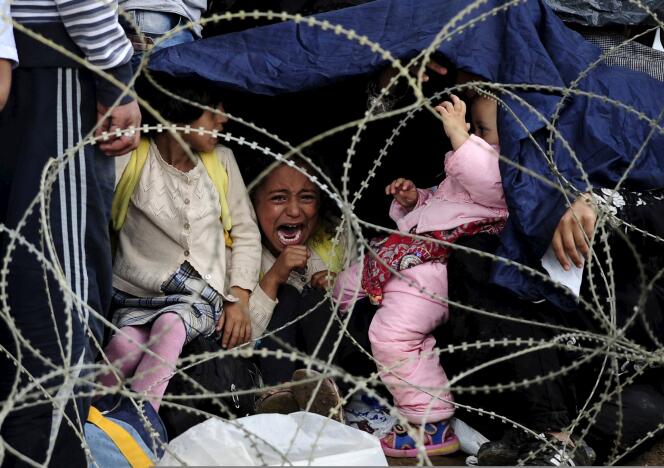 Des familles de réfugiés attendent sous la pluie de passer la frontière entre la Grèce et la Macédoine, samedi 22 août.
