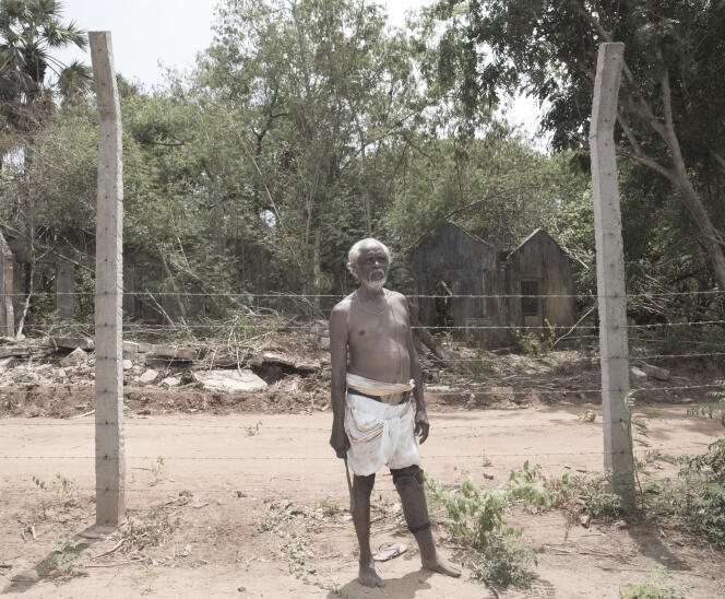 Subnamanigaiyar Kugathasasanma, devant sa maison en ruine, quittée dans la précipitation il y a vingt-cinq ans.