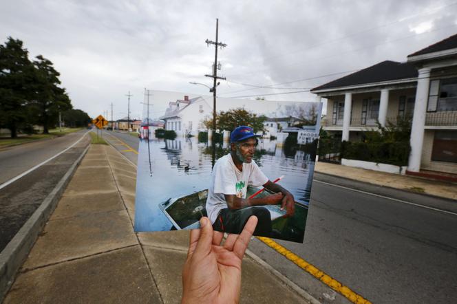 Le photographe Carlos Barria tient un tirage d’une photo qu’il a prise en 2005 au même endroit, dix ans plus tard, à La Nouvelle-Orléans (Etats-Unis), le 16 août 2015. Le cliché montre Errol Morning assis dans son bateau après le passage de l’ouragan Katrina. - CARLOS BARRIA/REUTERS
