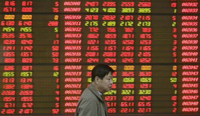 Un épargnant chinois passe devant un écran électronique montrant les cotations d'actions chinoises, à Pékin.